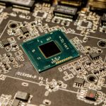 Close de um microchip instalado em uma placa de circuito, com componentes eletrônicos ao redor