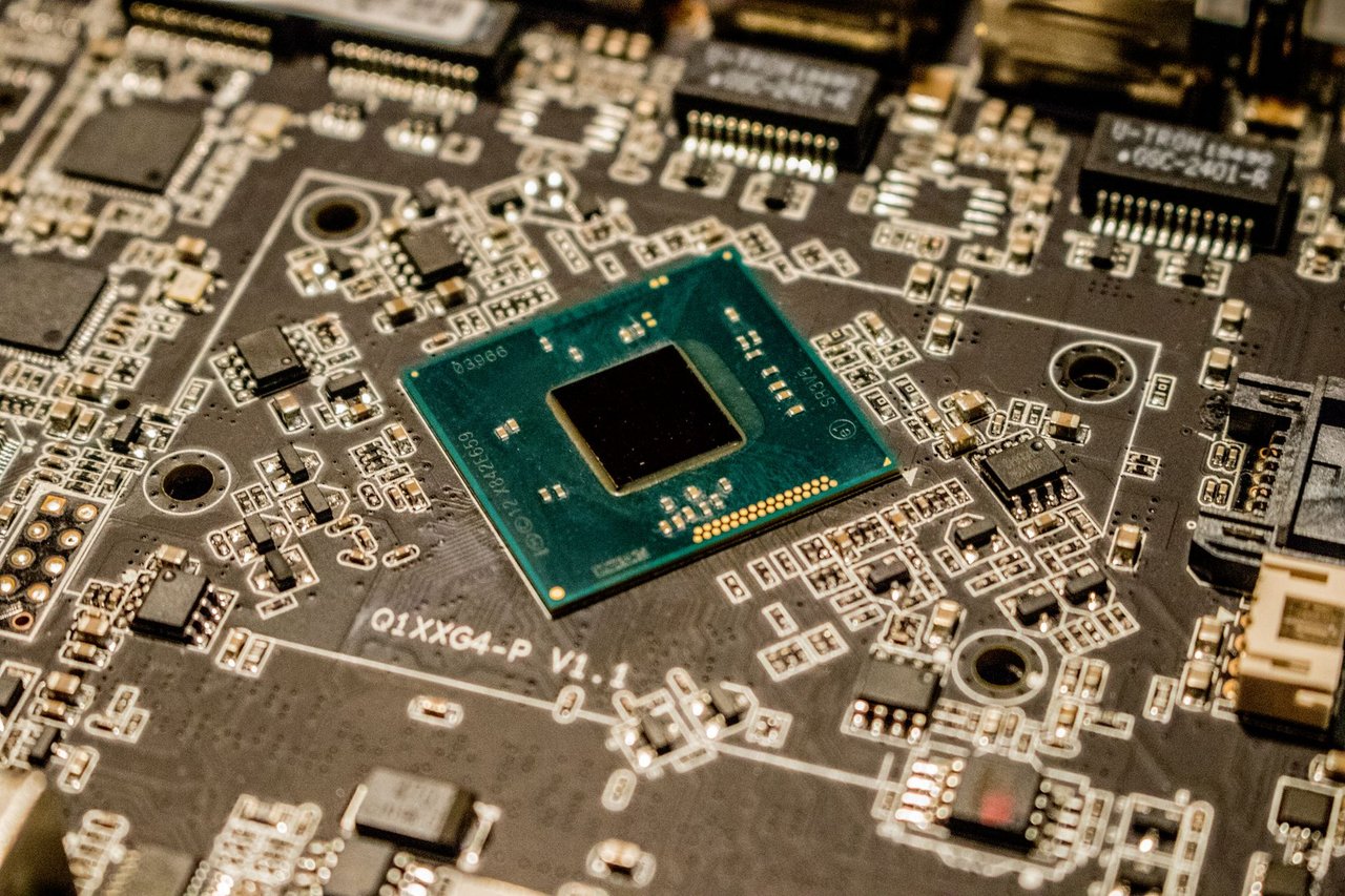 Close de um microchip instalado em uma placa de circuito, com componentes eletrônicos ao redor